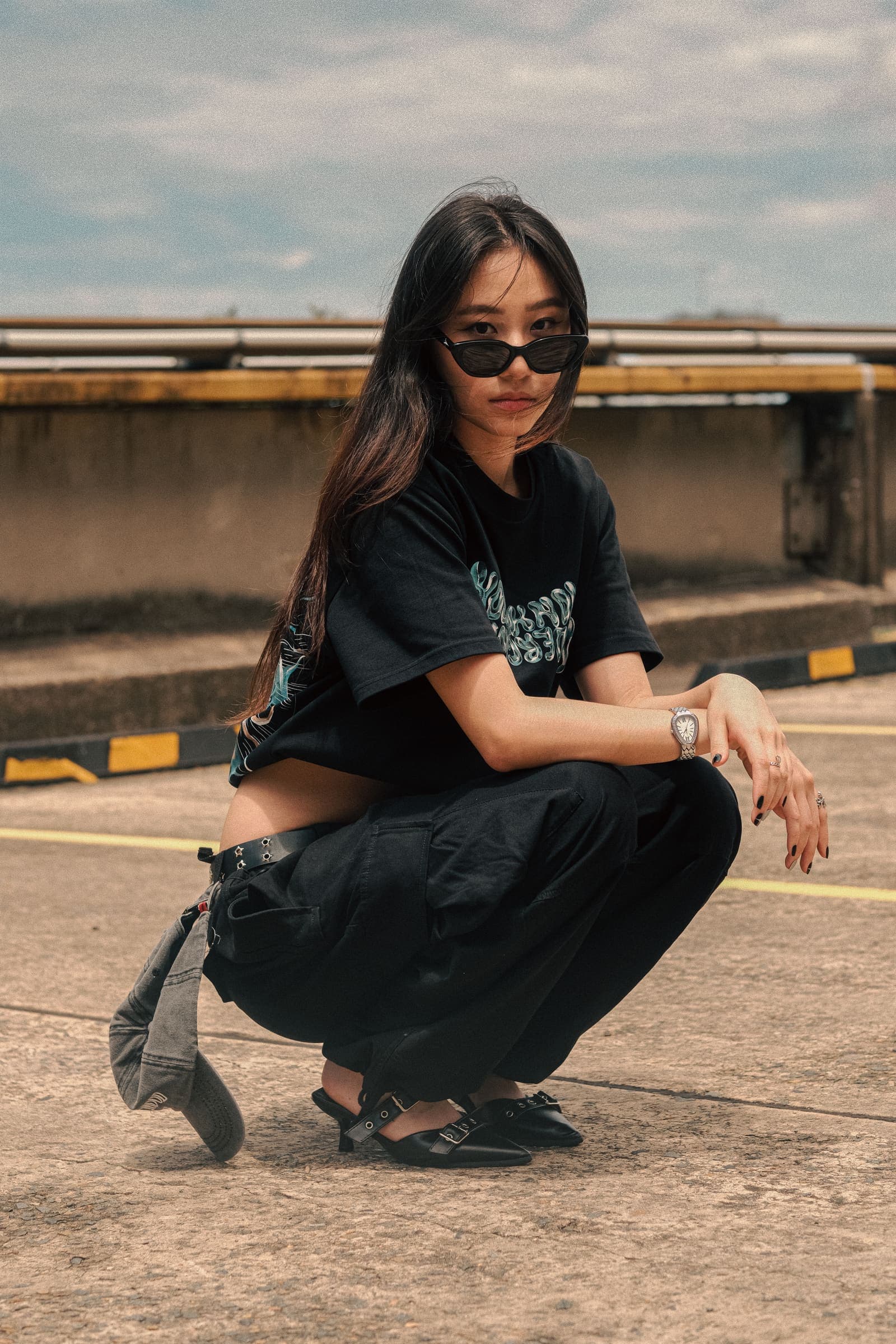A model in the black Nowuknow tee crouching on a rooftop car park