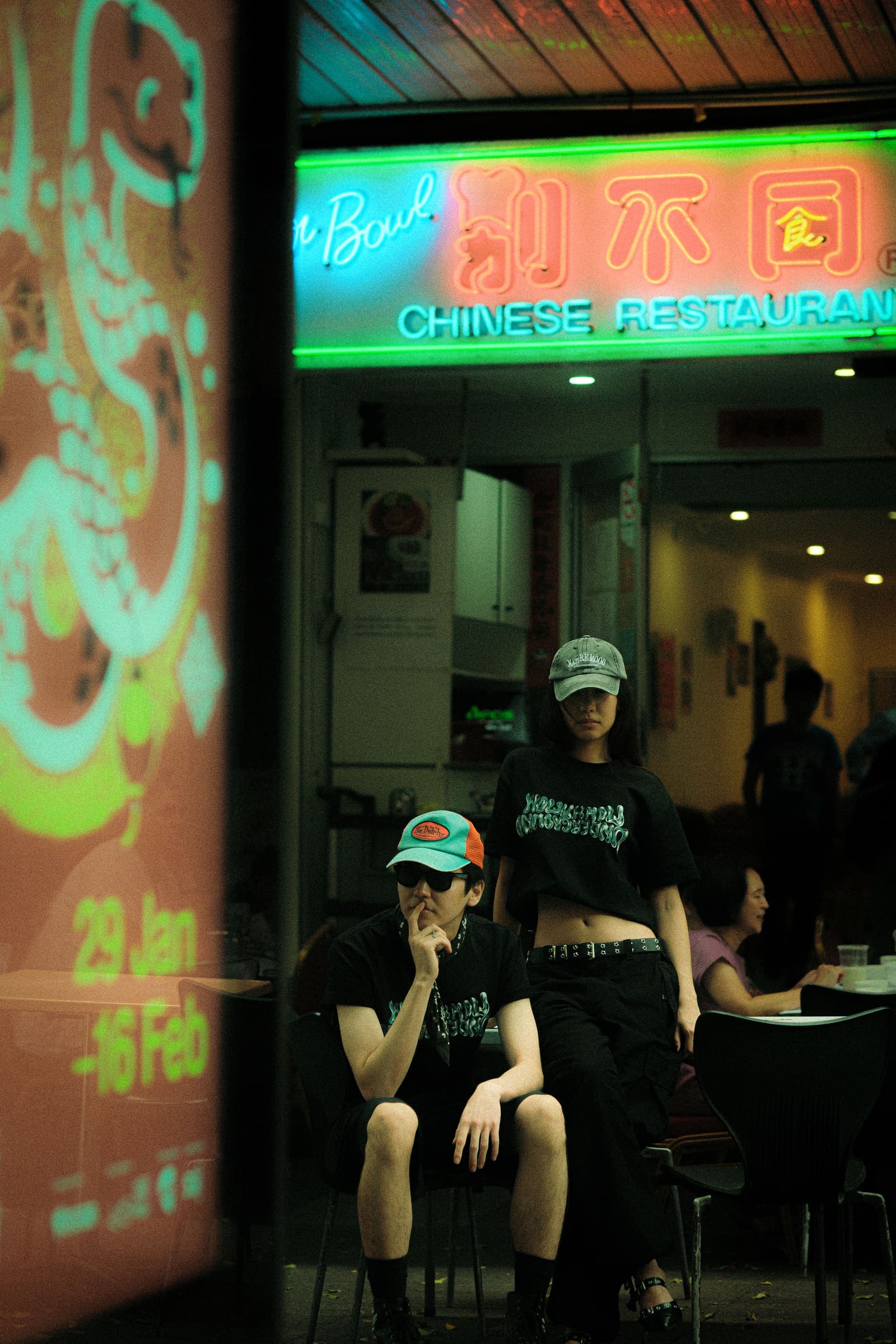 Two models outside a Chinese restaurant under green and red neon