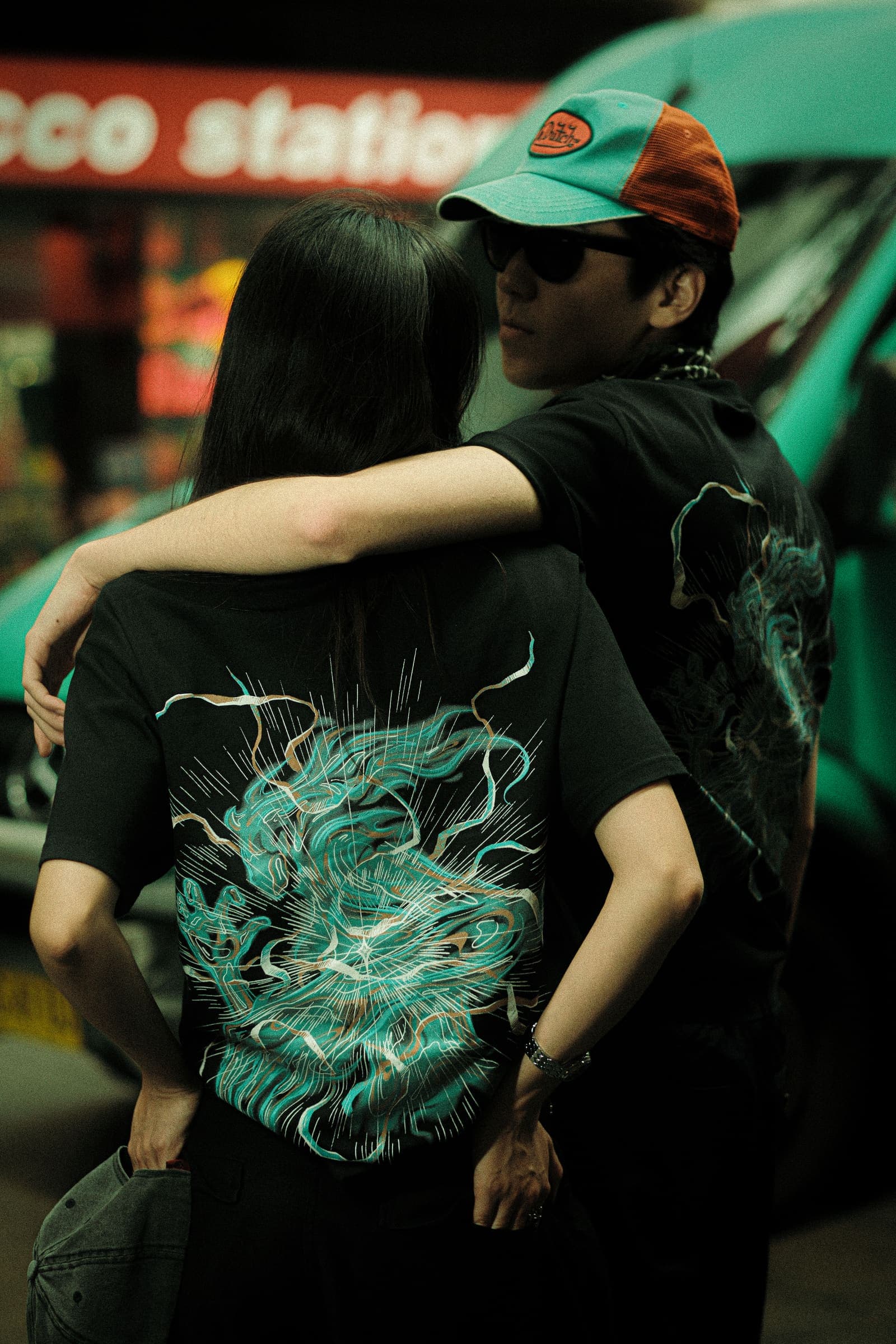 The back print, an arm around the shoulders, beside a teal van